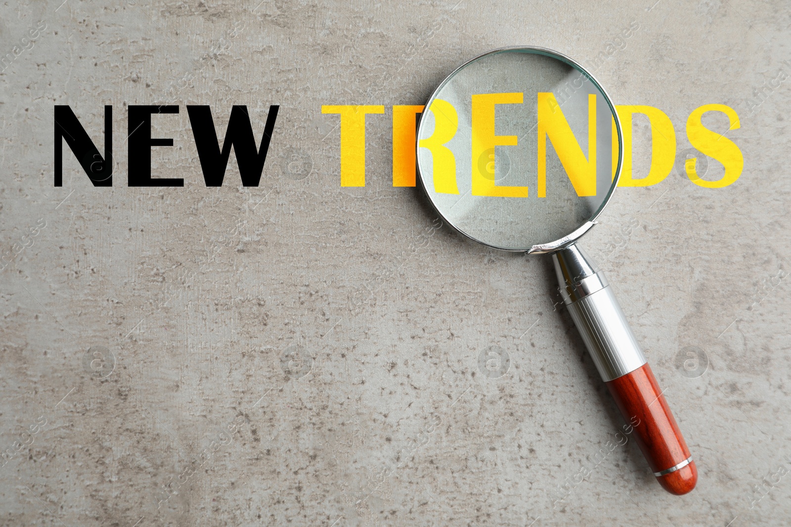 New trends. Magnifying glass on grey textured background, top view Image of New trends. Magnifying glass on grey textured background, top view