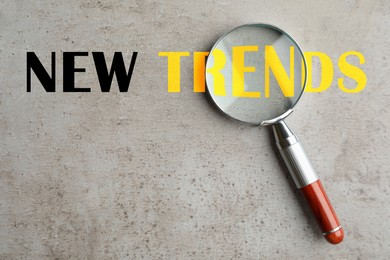 Image of New trends. Magnifying glass on grey textured background, top view