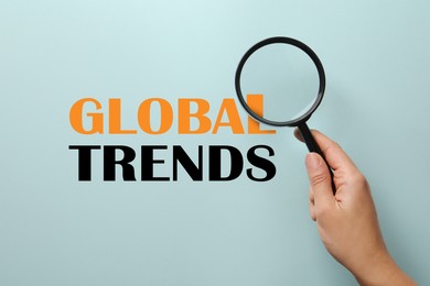 Image of Words Global Trends, view through magnifying glass in woman's hand
