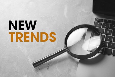 Image of New trends. Magnifying glass and laptop on grey table