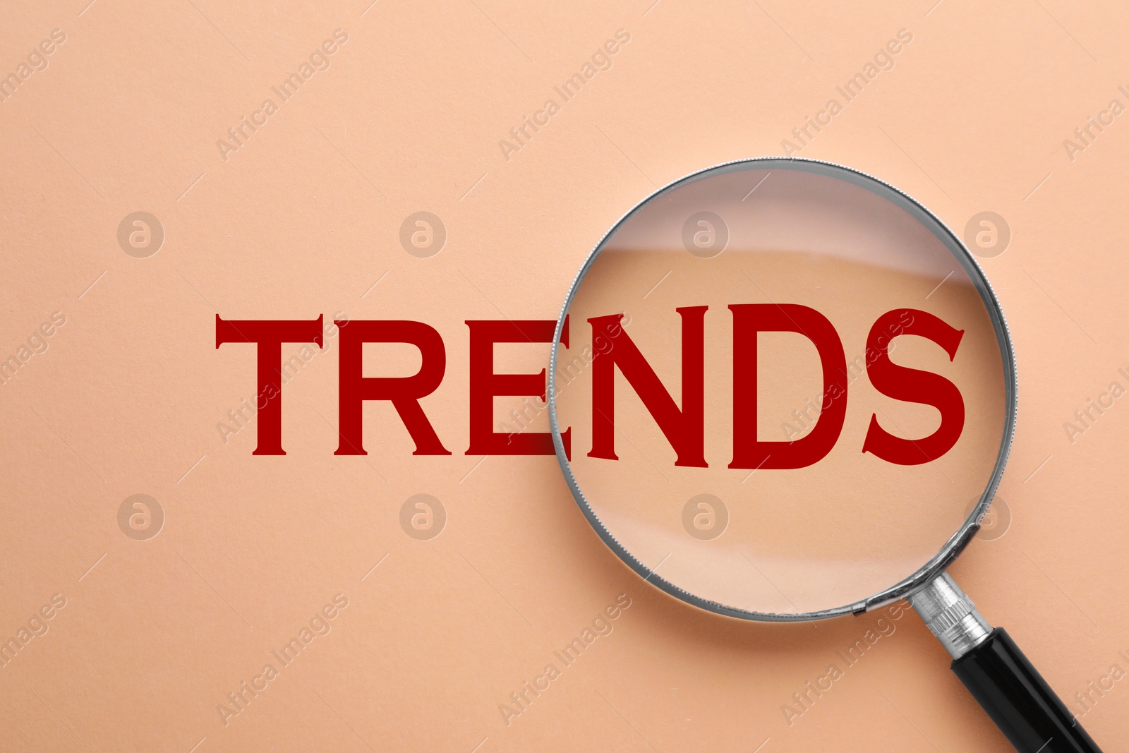 Word Trends and magnifying glass on dark beige background, top view Image of Word Trends and magnifying glass on dark beige background, top view