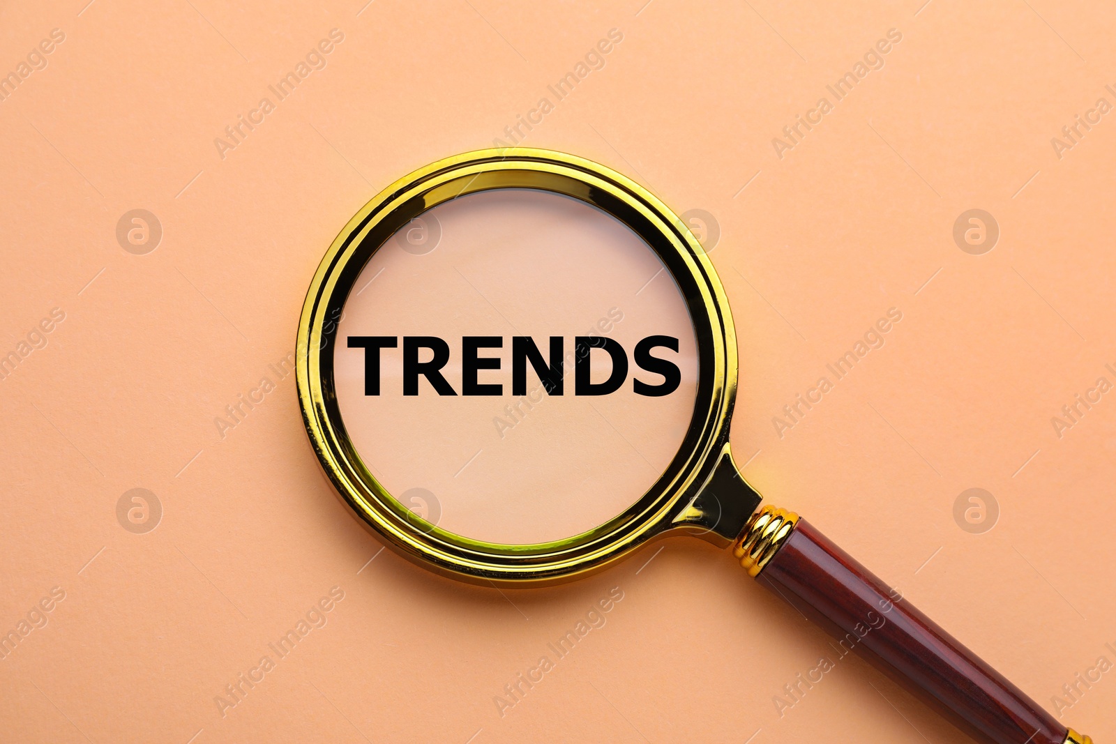 Word Trends and magnifying glass on dark beige background, top view Image of Word Trends and magnifying glass on dark beige background, top view