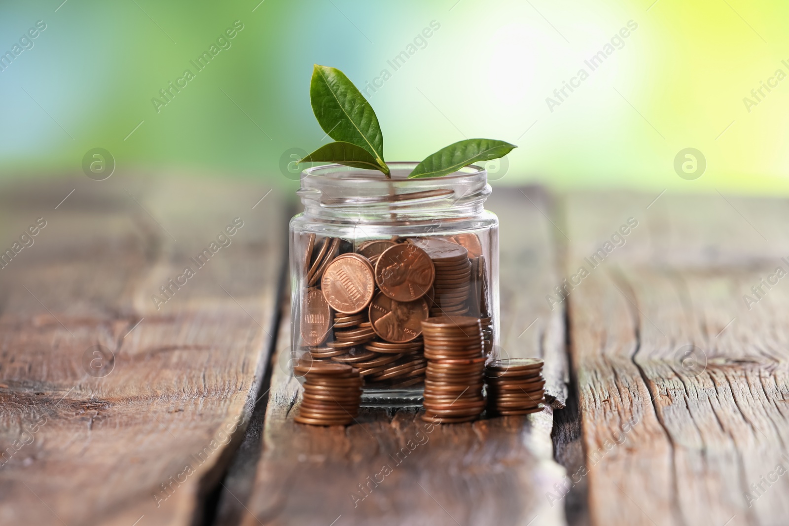 Investment concept. Glass jar with coins and sprout on wooden table against blurred green background Photo of Investment concept. Glass jar with coins and sprout on wooden table against blurred green background