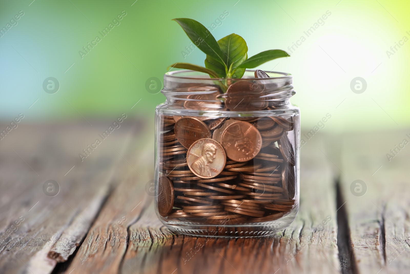 Investment concept. Glass jar with coins and sprout on wooden table against blurred green background Photo of Investment concept. Glass jar with coins and sprout on wooden table against blurred green background