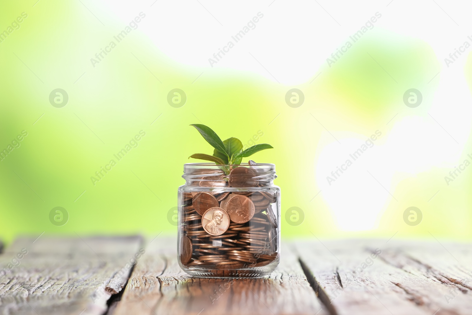 Investment concept. Glass jar with coins and sprout on wooden table against blurred green background Photo of Investment concept. Glass jar with coins and sprout on wooden table against blurred green background