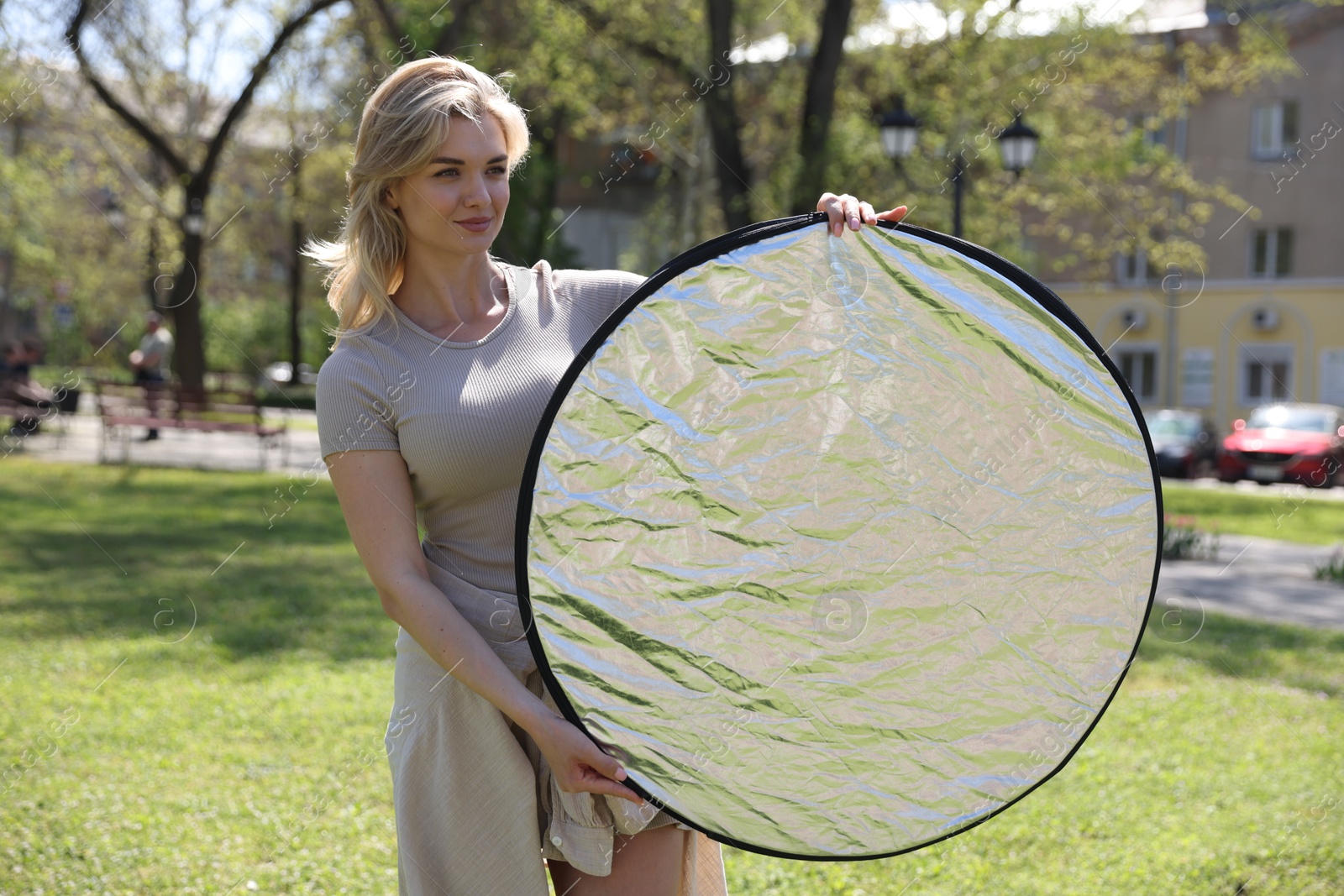 Photo of Woman with reflector outdoors on sunny day. Photography equipment