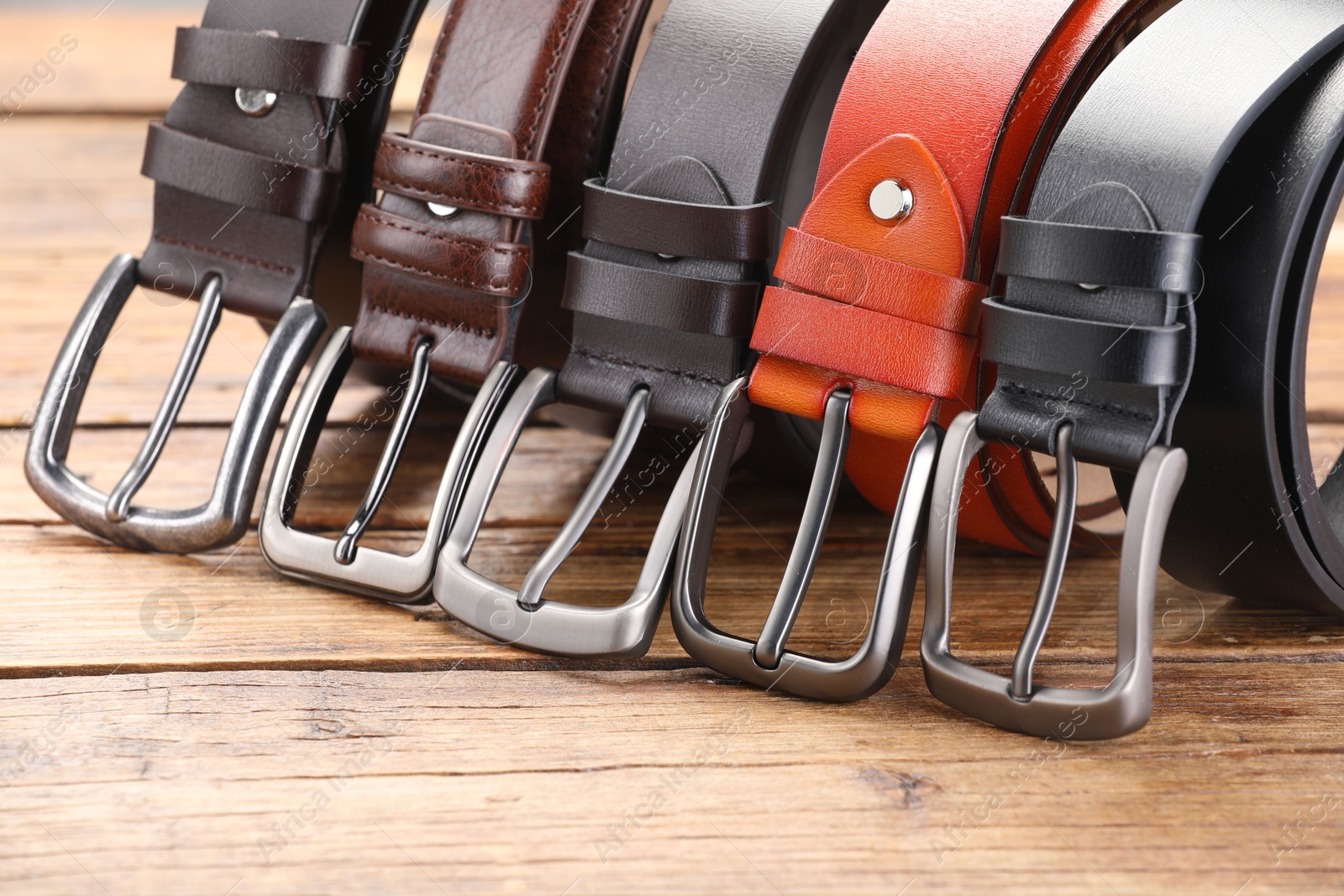 Many different leather belts on wooden table, closeup Photo of Many different leather belts on wooden table, closeup
