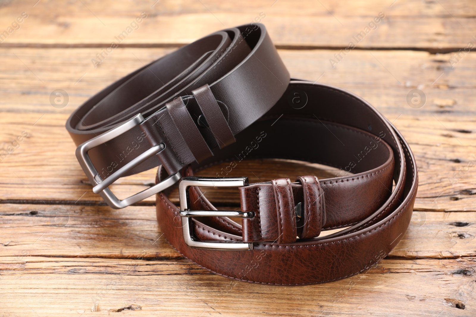 Two leather belts on wooden table, closeup Photo of Two leather belts on wooden table, closeup