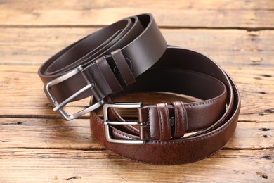 Photo of Two leather belts on wooden table, closeup