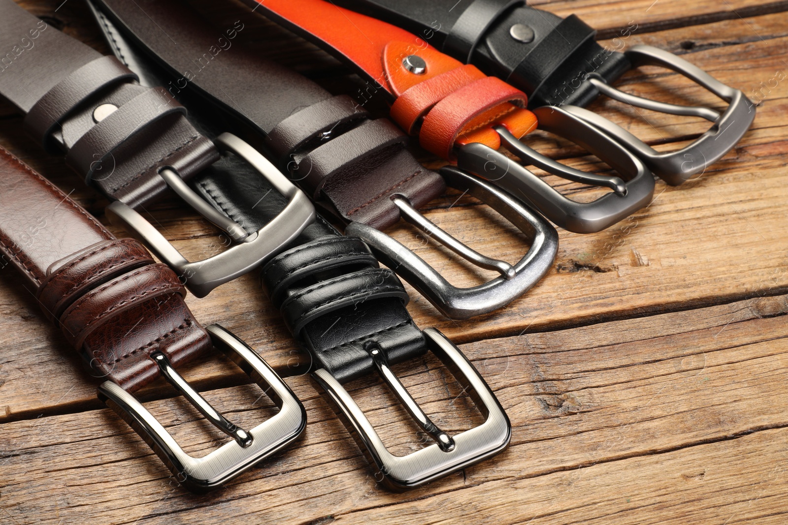 Many different leather belts on wooden table, closeup Photo of Many different leather belts on wooden table, closeup