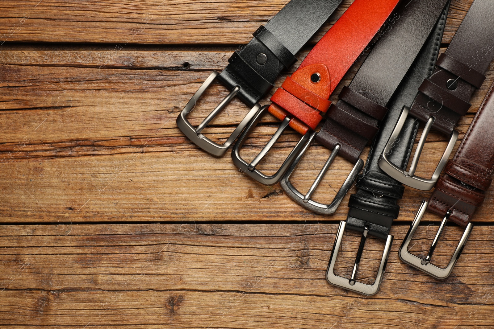 Many different leather belts on wooden table, flat lay. Space for text Photo of Many different leather belts on wooden table, flat lay. Space for text
