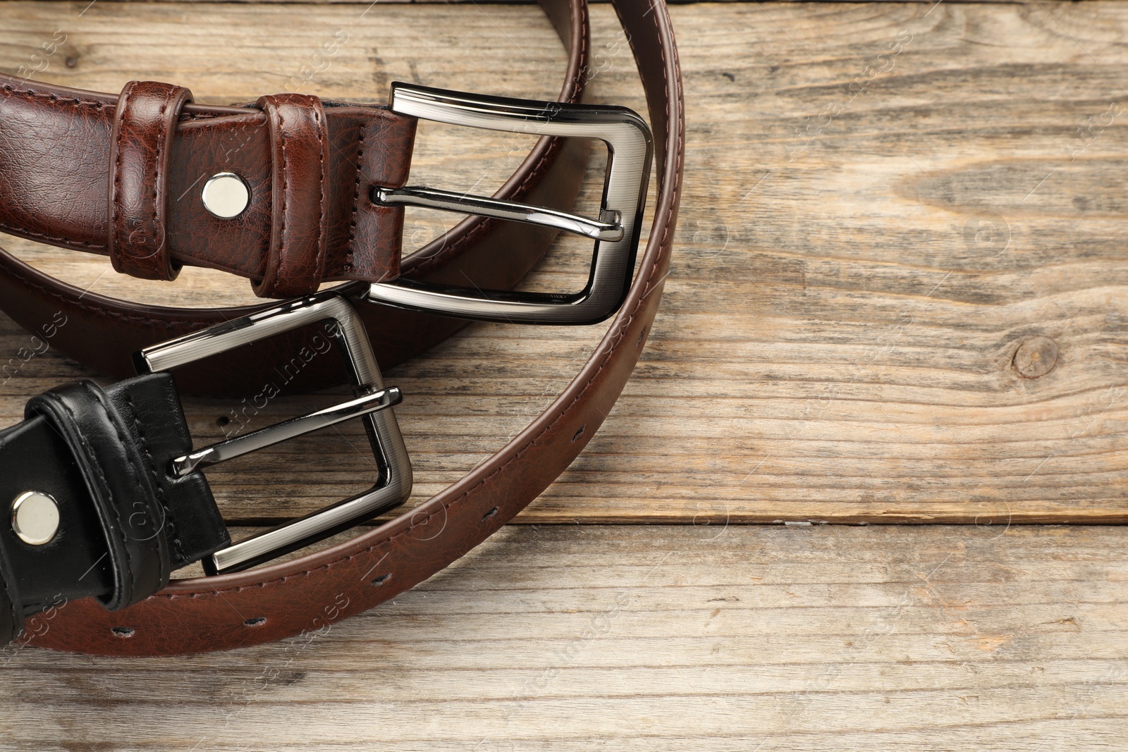 Two leather belts on wooden table, above view. Space for text Photo of Two leather belts on wooden table, above view. Space for text