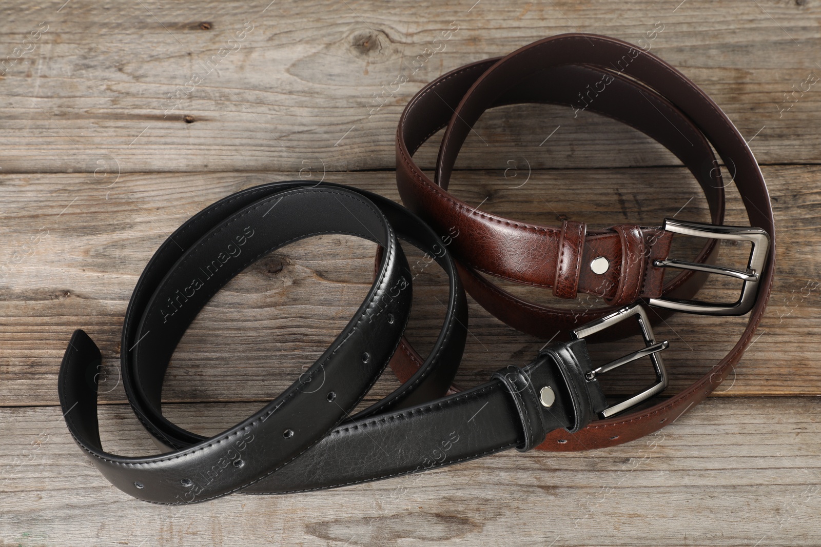 Two leather belts on wooden table, above view Photo of Two leather belts on wooden table, above view