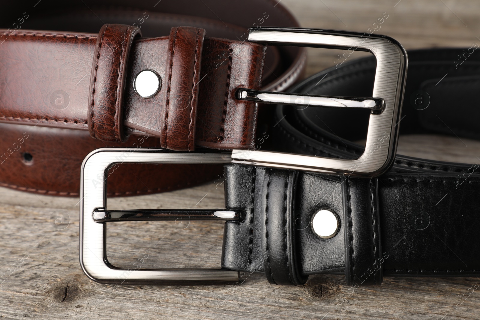Two leather belts on wooden table, closeup Photo of Two leather belts on wooden table, closeup