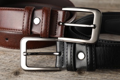 Photo of Two leather belts on wooden table, closeup