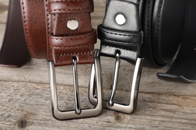 Photo of Two leather belts on wooden table, closeup