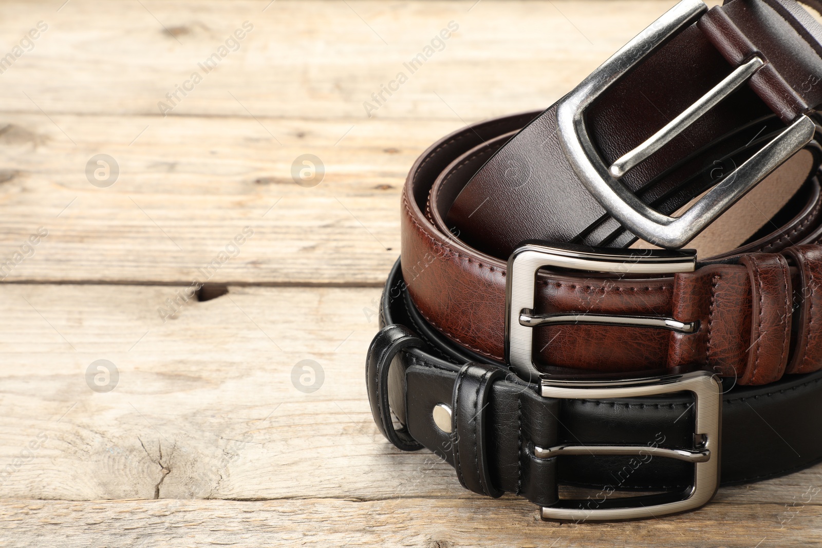 Three leather belts on wooden table, closeup. Space for text Photo of Three leather belts on wooden table, closeup. Space for text