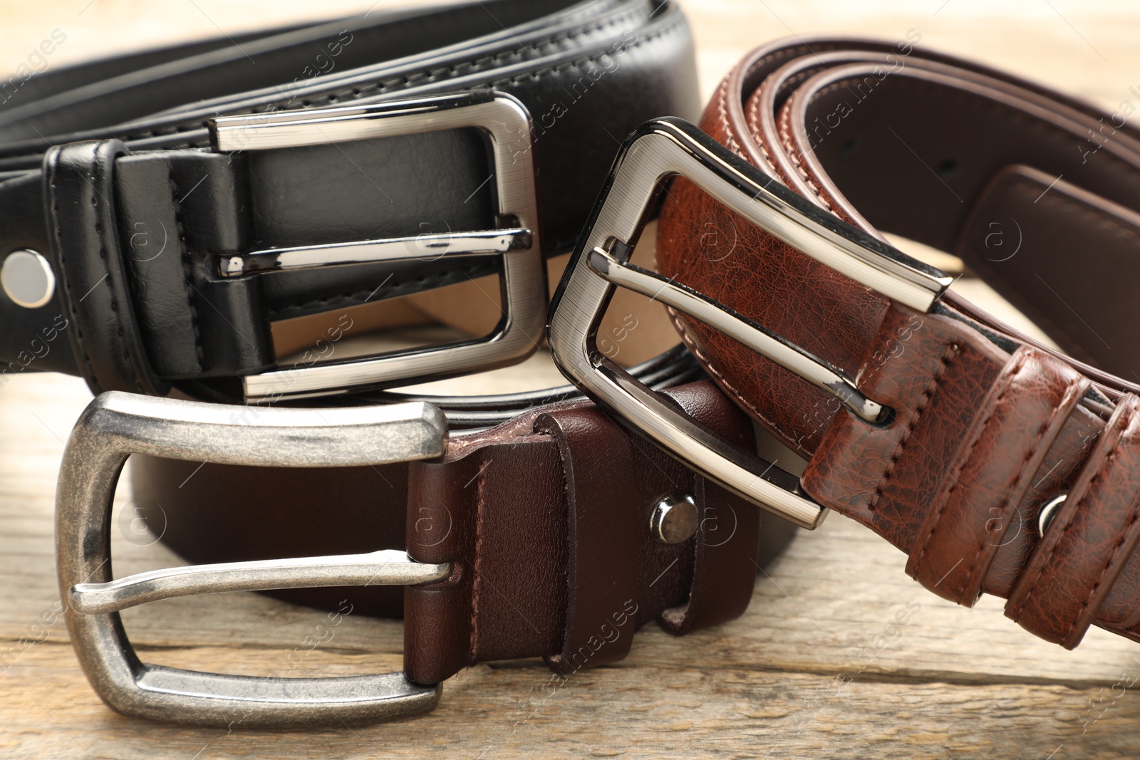 Three leather belts on wooden table, closeup Photo of Three leather belts on wooden table, closeup