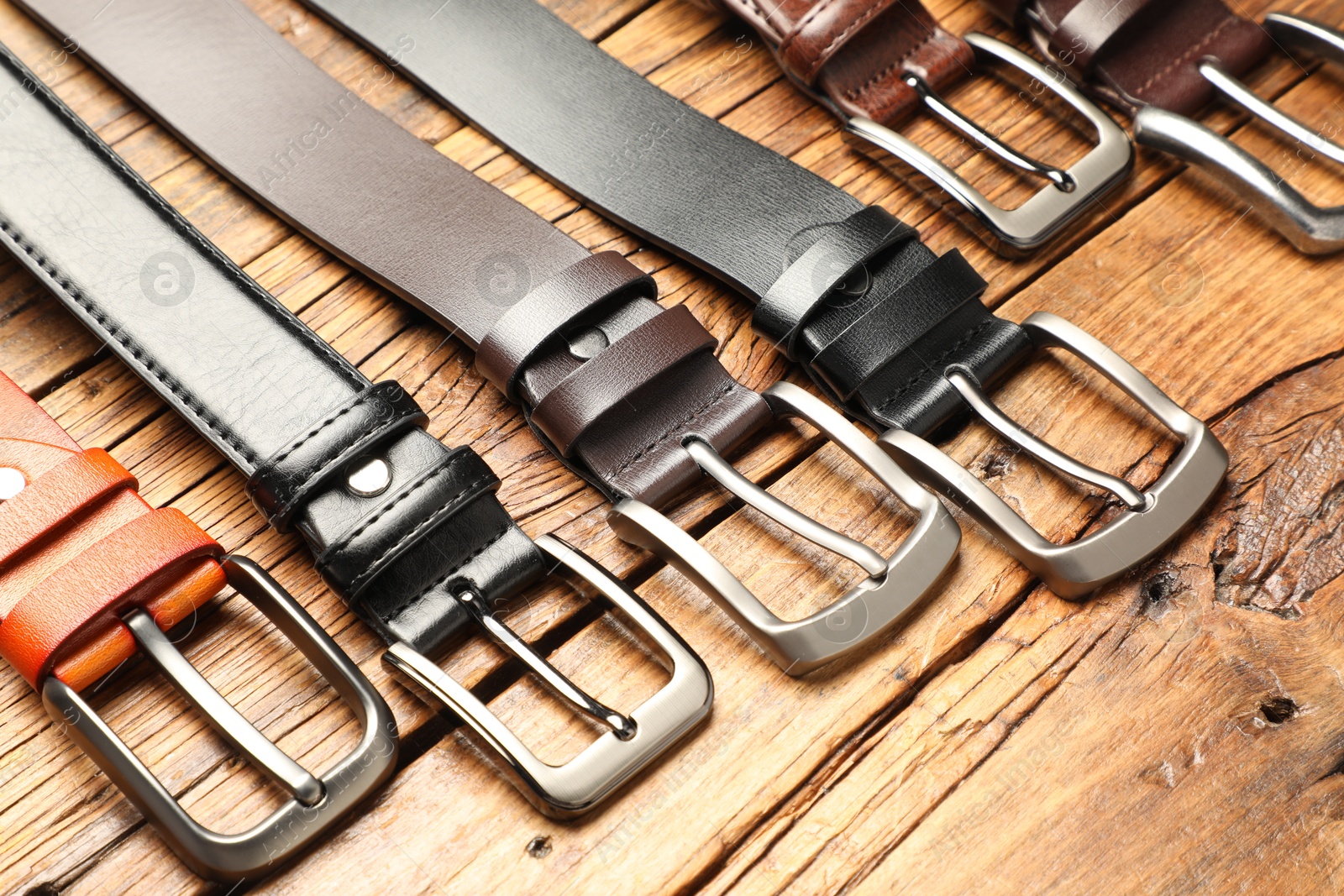 Many different leather belts on wooden table, above view Photo of Many different leather belts on wooden table, above view