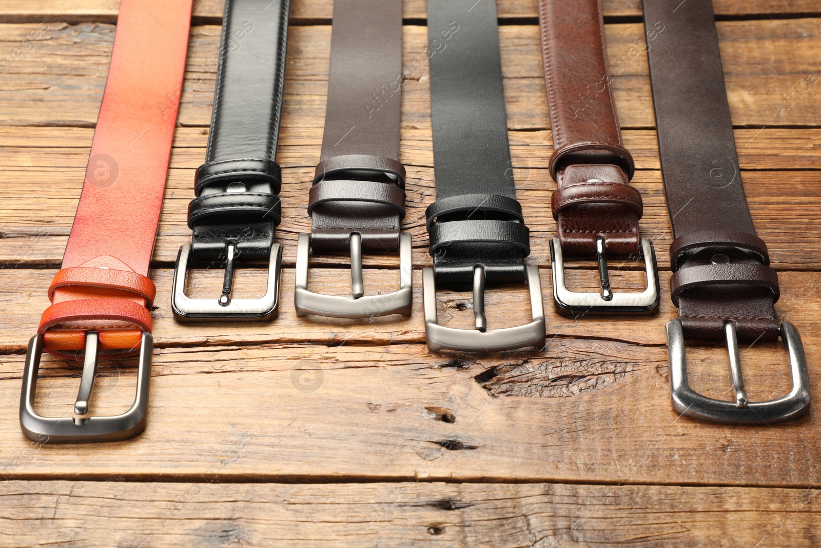 Many different leather belts on wooden table, above view Photo of Many different leather belts on wooden table, above view