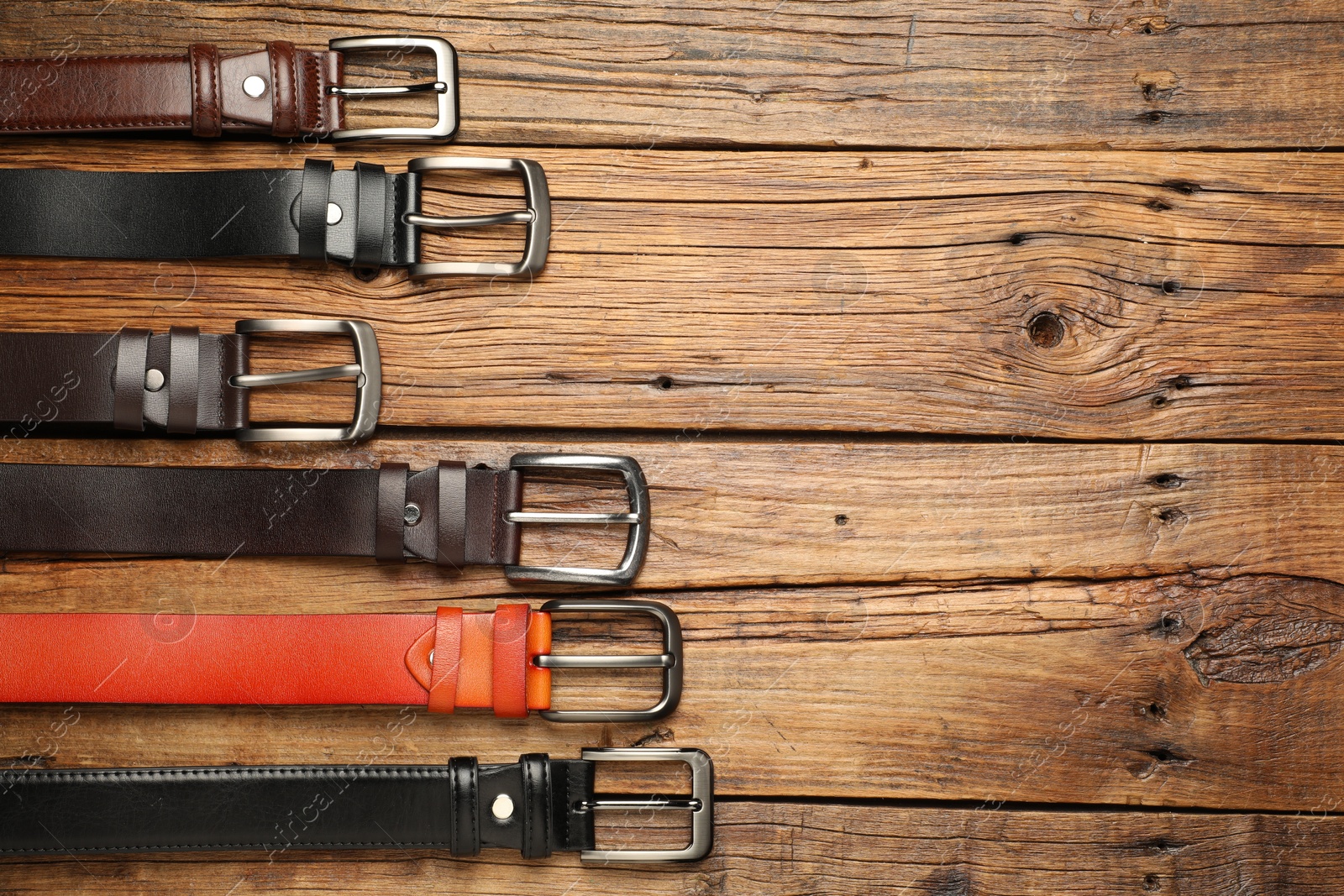 Many different leather belts on wooden table, flat lay. Space for text Photo of Many different leather belts on wooden table, flat lay. Space for text