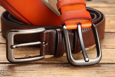 Photo of Two leather belts on wooden table, closeup