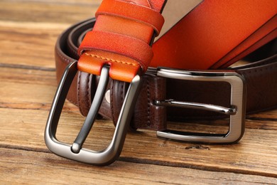 Photo of Two leather belts on wooden table, closeup
