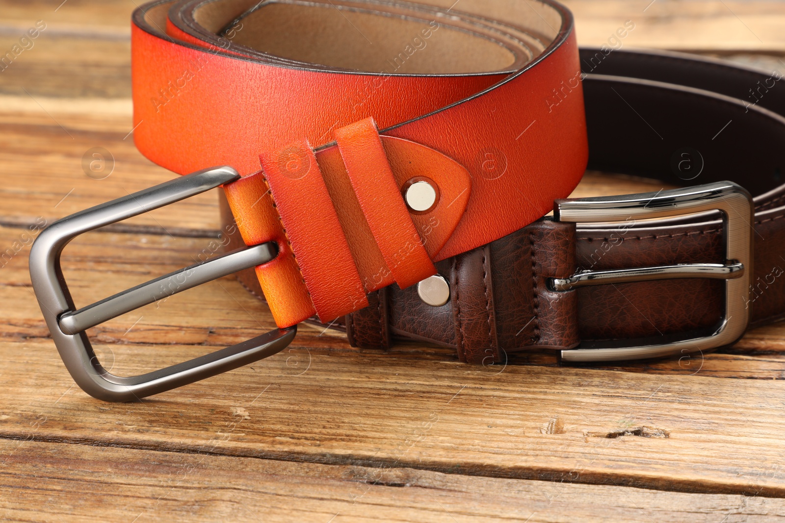 Two leather belts on wooden table, closeup Photo of Two leather belts on wooden table, closeup