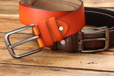 Photo of Two leather belts on wooden table, closeup