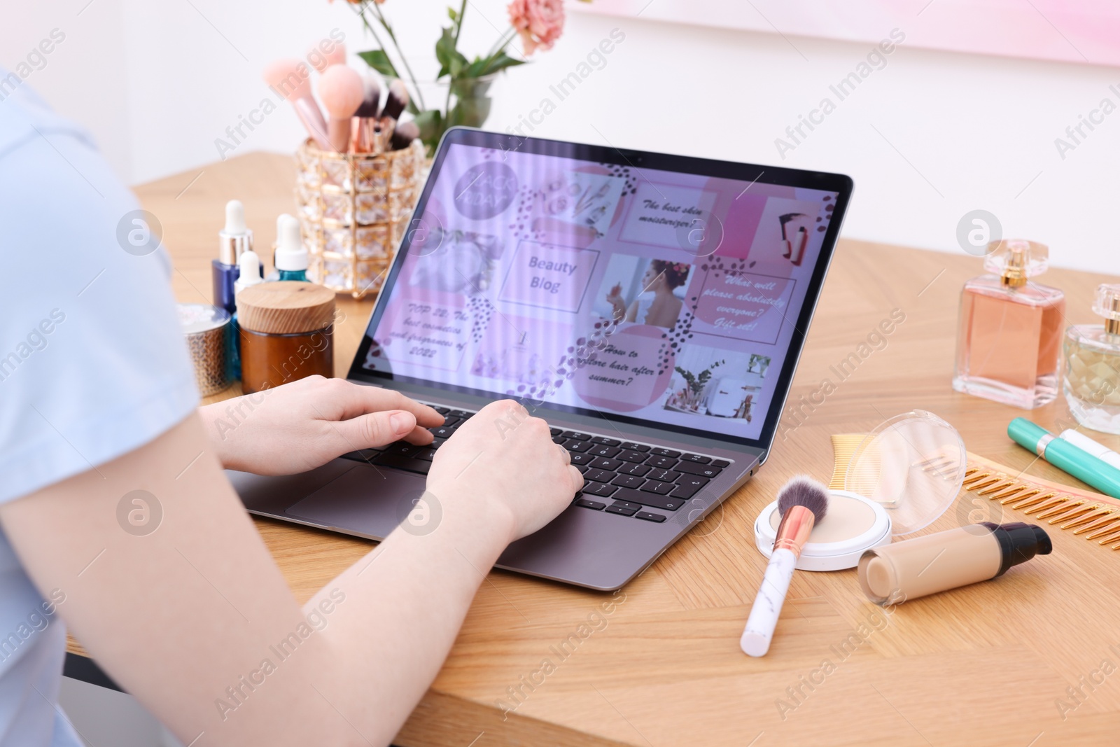 Blogger using laptop with beauty blog web site at wooden table indoors, closeup Photo of Blogger using laptop with beauty blog web site at wooden table indoors, closeup
