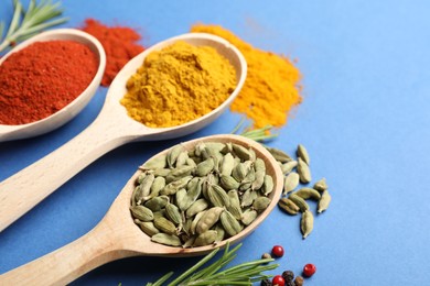 Photo of Different aromatic spices in spoons on blue background, closeup