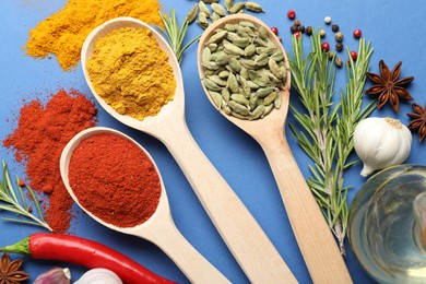 Photo of Different aromatic spices in spoons on blue background, flat lay