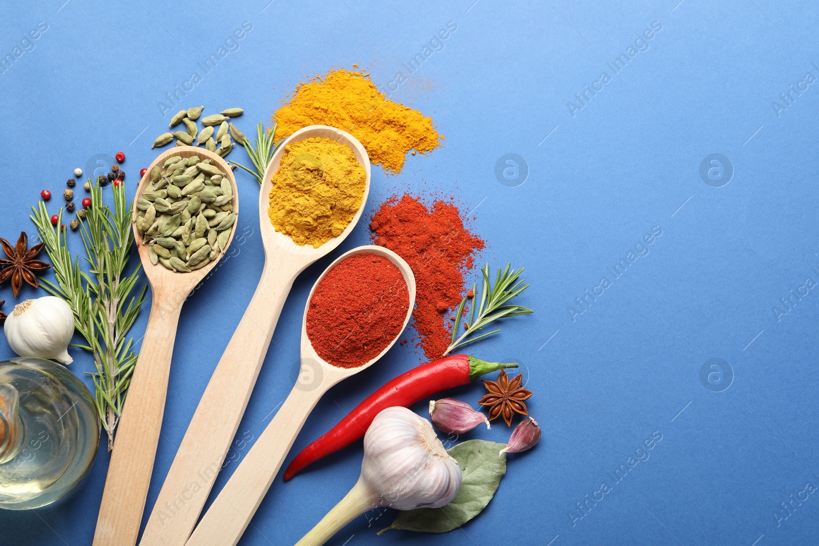 Different aromatic spices in spoons on blue background, flat lay. Space for text Photo of Different aromatic spices in spoons on blue background, flat lay. Space for text