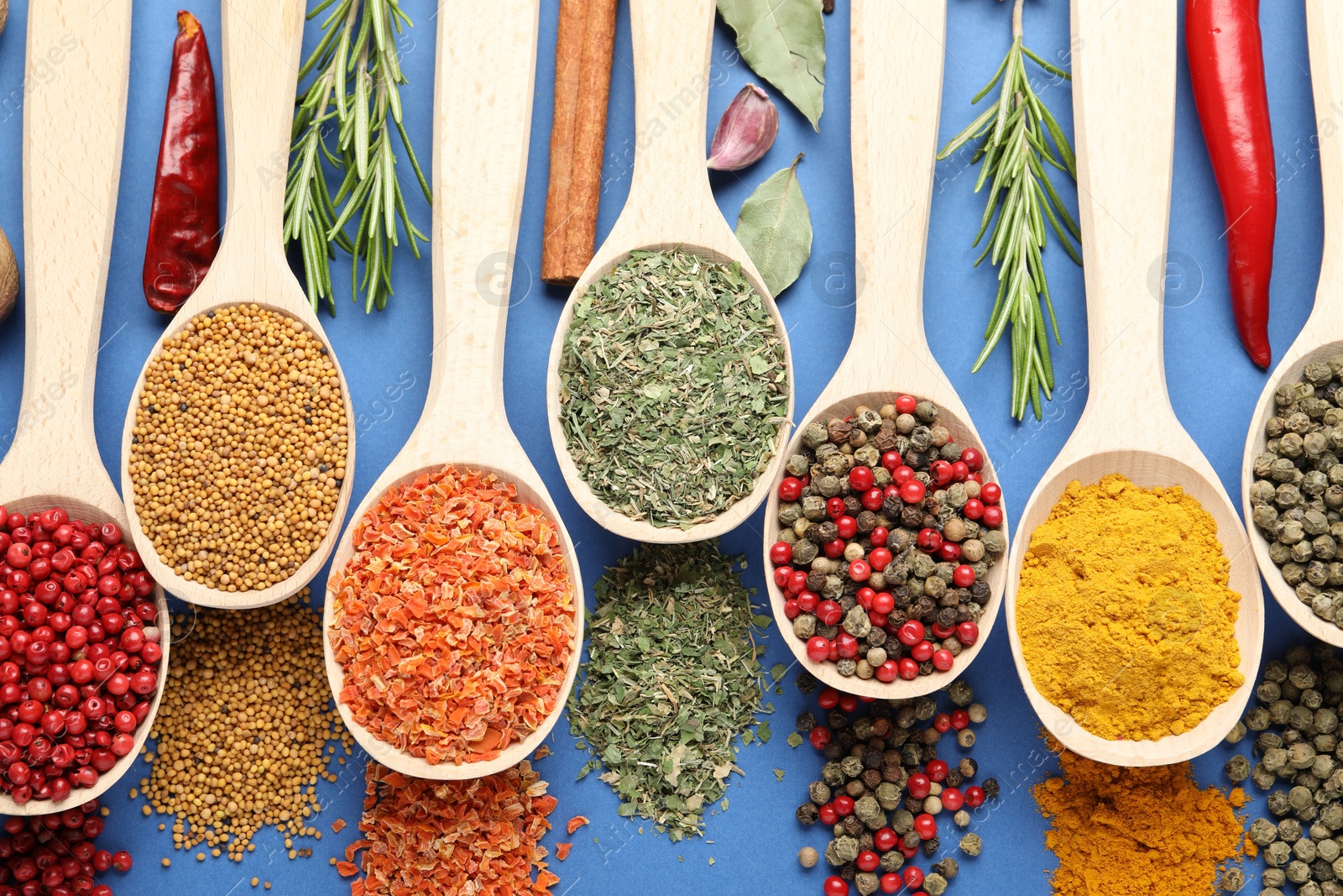 Different aromatic spices in spoons on blue background, flat lay Photo of Different aromatic spices in spoons on blue background, flat lay