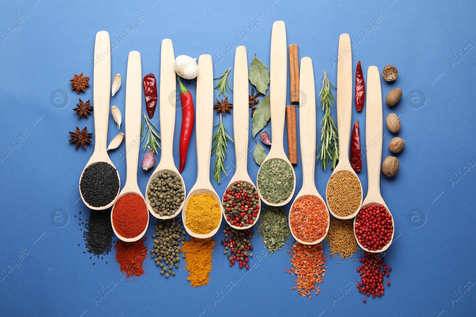 Different aromatic spices in spoons on blue background, flat lay Photo of Different aromatic spices in spoons on blue background, flat lay