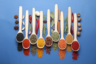 Photo of Different aromatic spices in spoons on blue background, flat lay