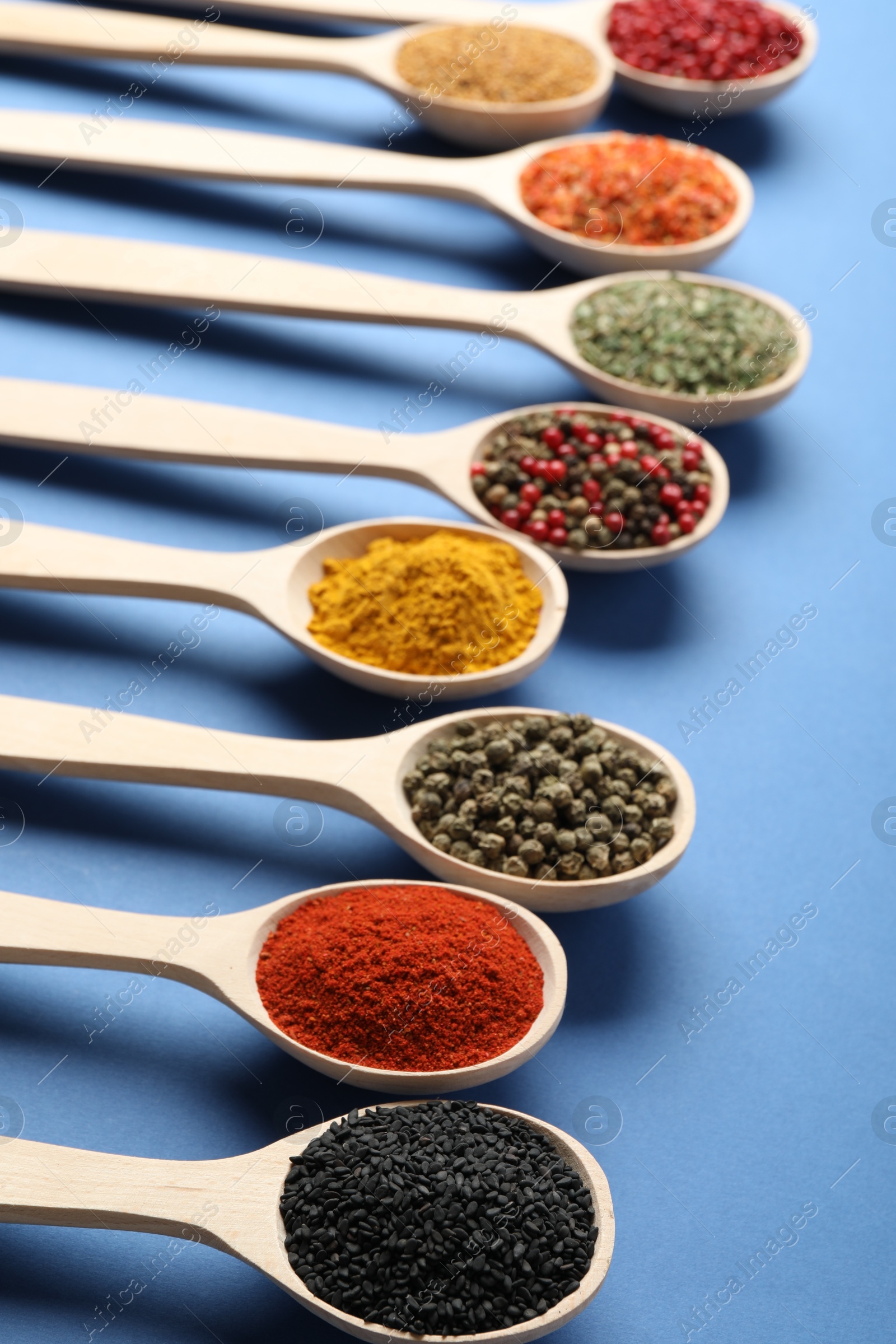Different aromatic spices in spoons on blue background, closeup Photo of Different aromatic spices in spoons on blue background, closeup