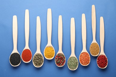 Photo of Different aromatic spices in spoons on blue background, flat lay