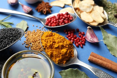 Photo of Different aromatic spices and oil on blue background, closeup
