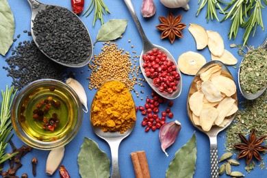 Photo of Different aromatic spices and oil on blue background, flat lay
