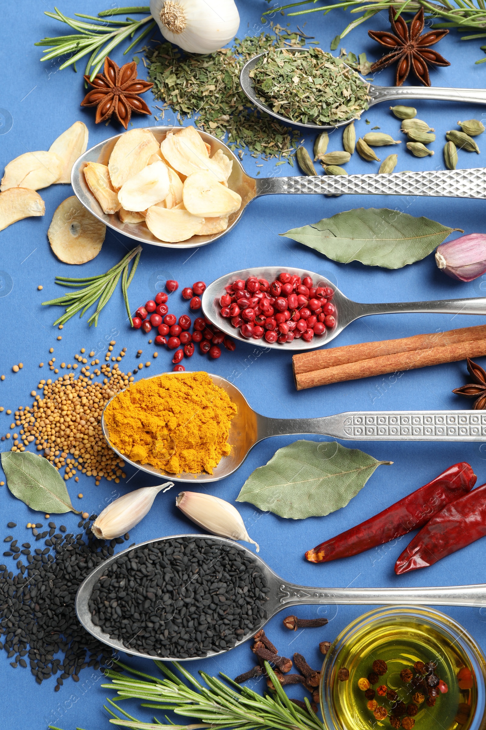 Different aromatic spices and oil on blue background, flat lay Photo of Different aromatic spices and oil on blue background, flat lay