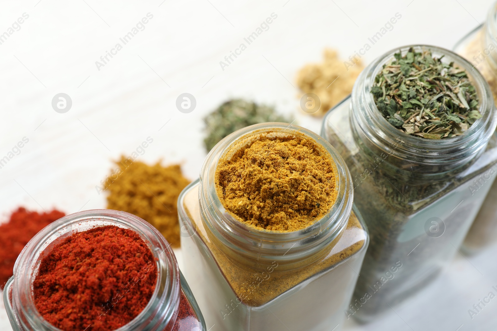 Different aromatic spices in jars on white table, closeup Photo of Different aromatic spices in jars on white table, closeup