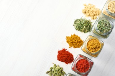 Photo of Different aromatic spices in jars on white table, flat lay. Space for text