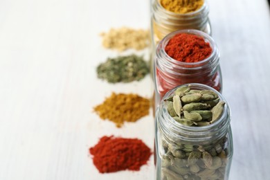 Photo of Different aromatic spices in jars on white table, closeup. Space for text