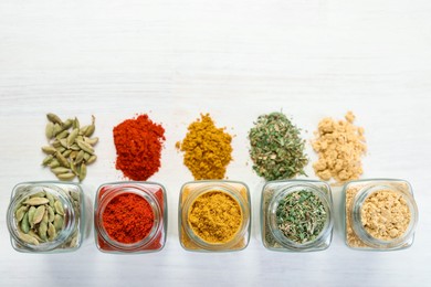 Photo of Different aromatic spices in jars on white table, flat lay. Space for text