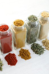 Photo of Different aromatic spices in jars on white table, closeup