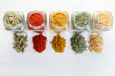 Photo of Different aromatic spices in jars on white table, flat lay