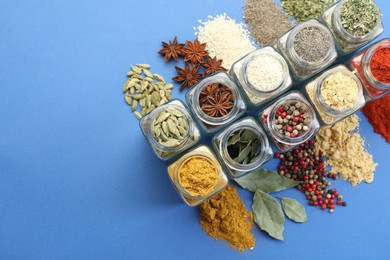 Photo of Different aromatic spices in jars on blue background, flat lay. Space for text