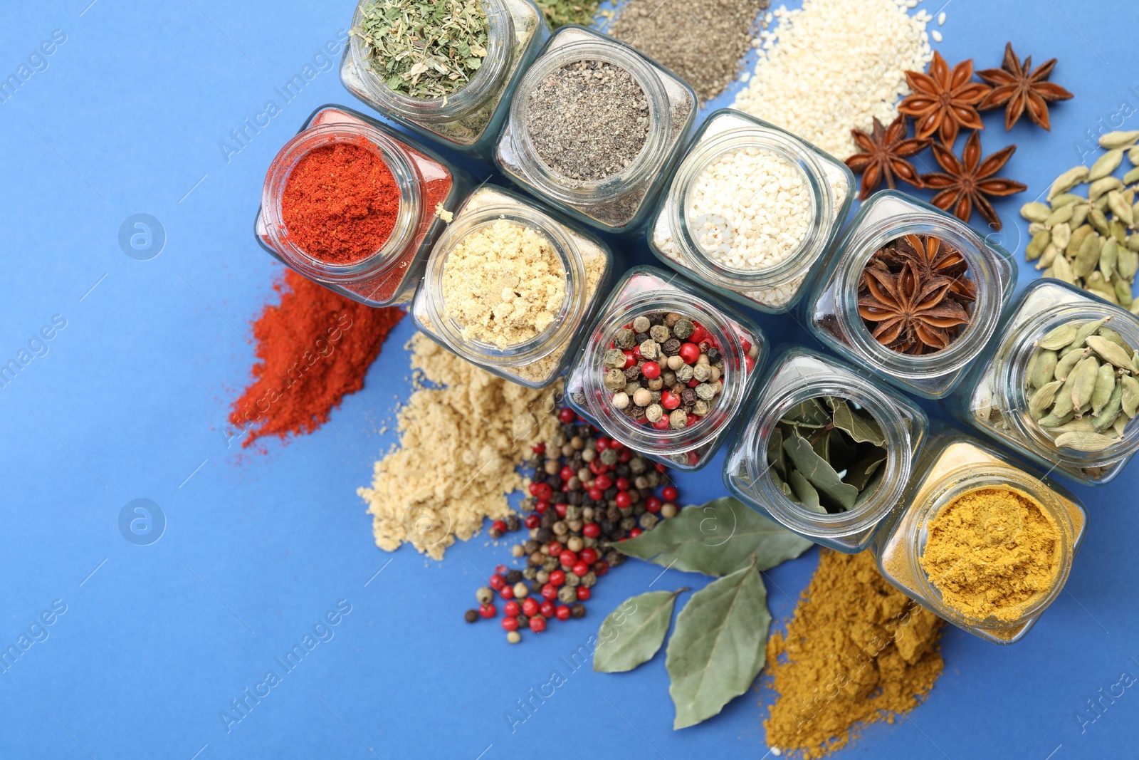 Different aromatic spices in jars on blue background, flat lay Photo of Different aromatic spices in jars on blue background, flat lay