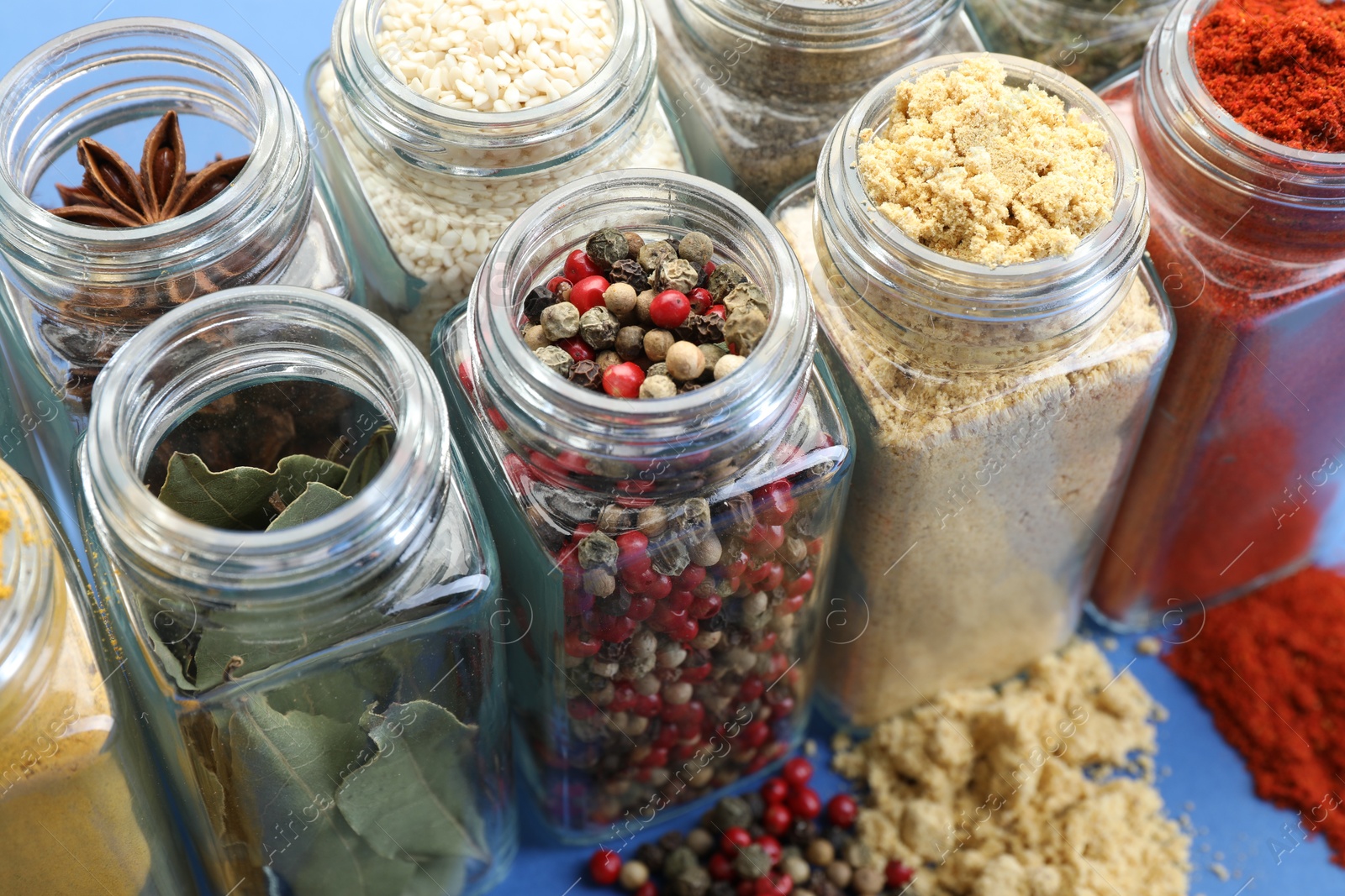 Different aromatic spices in jars on blue background, closeup Photo of Different aromatic spices in jars on blue background, closeup